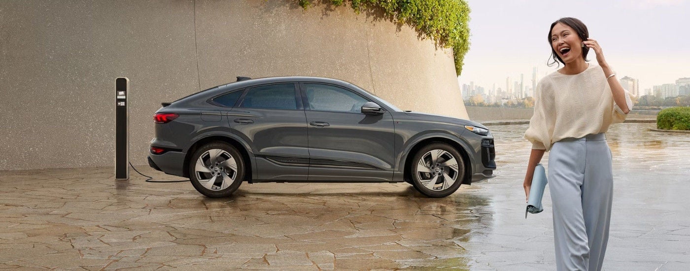 Laughing person walking near a grey 2025 Audi Q6 Sportback e-tron